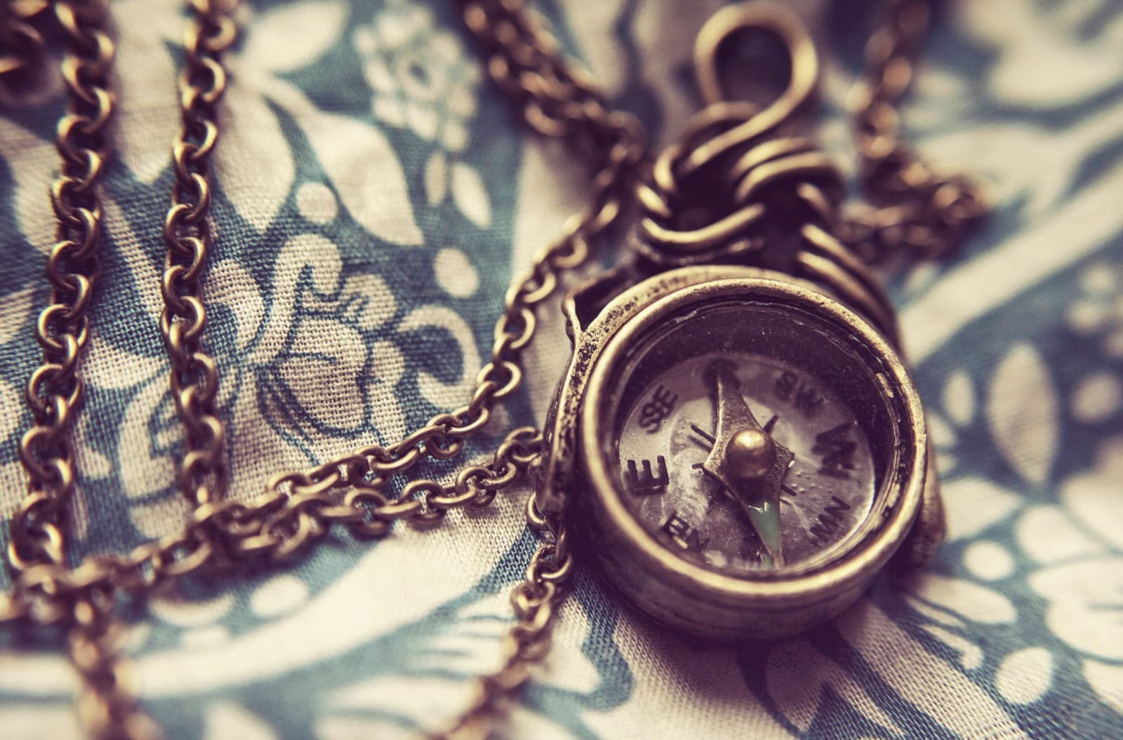 An antique brass pocket compass on a chain