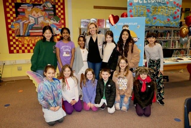 Liesl in a school library with students, some dressed as fairy-tale characters