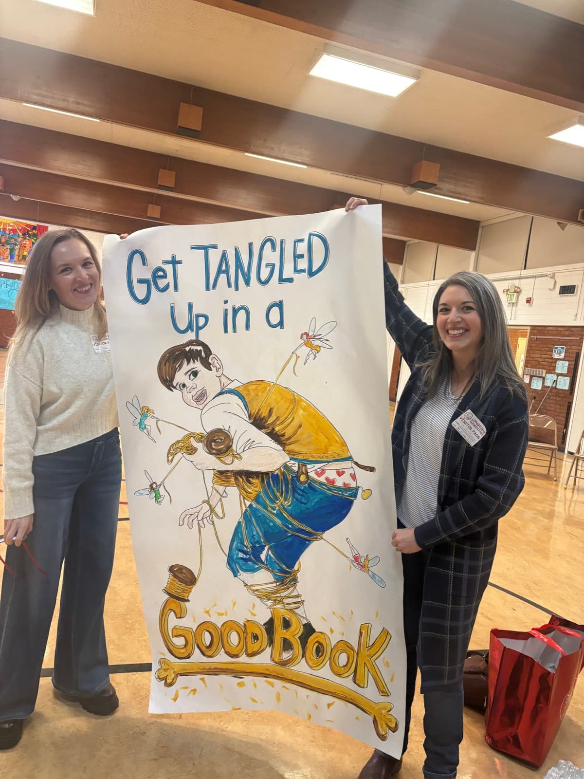 Liesl with a teacher holding a hand-painted “Get Tangled Up in a Good Book” RUMP banner