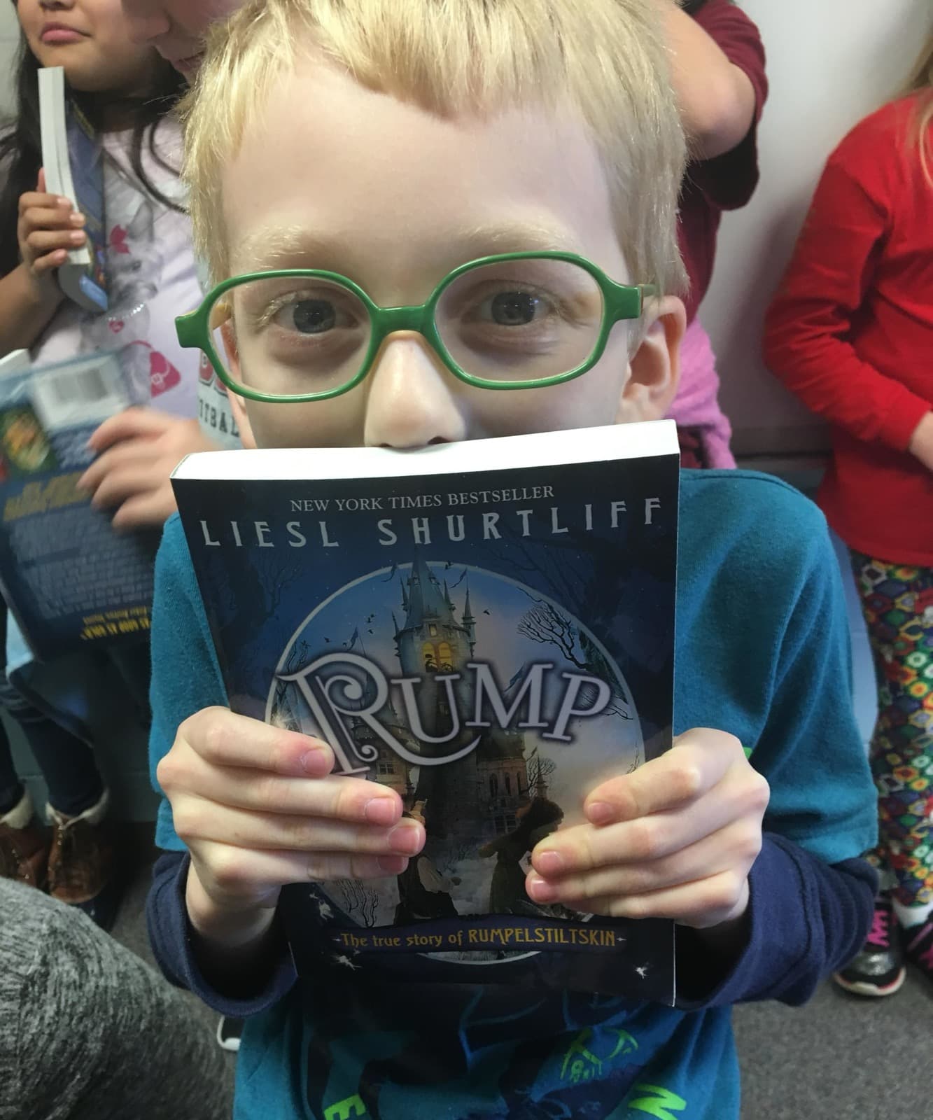 A smiling student peeking over a copy of RUMP