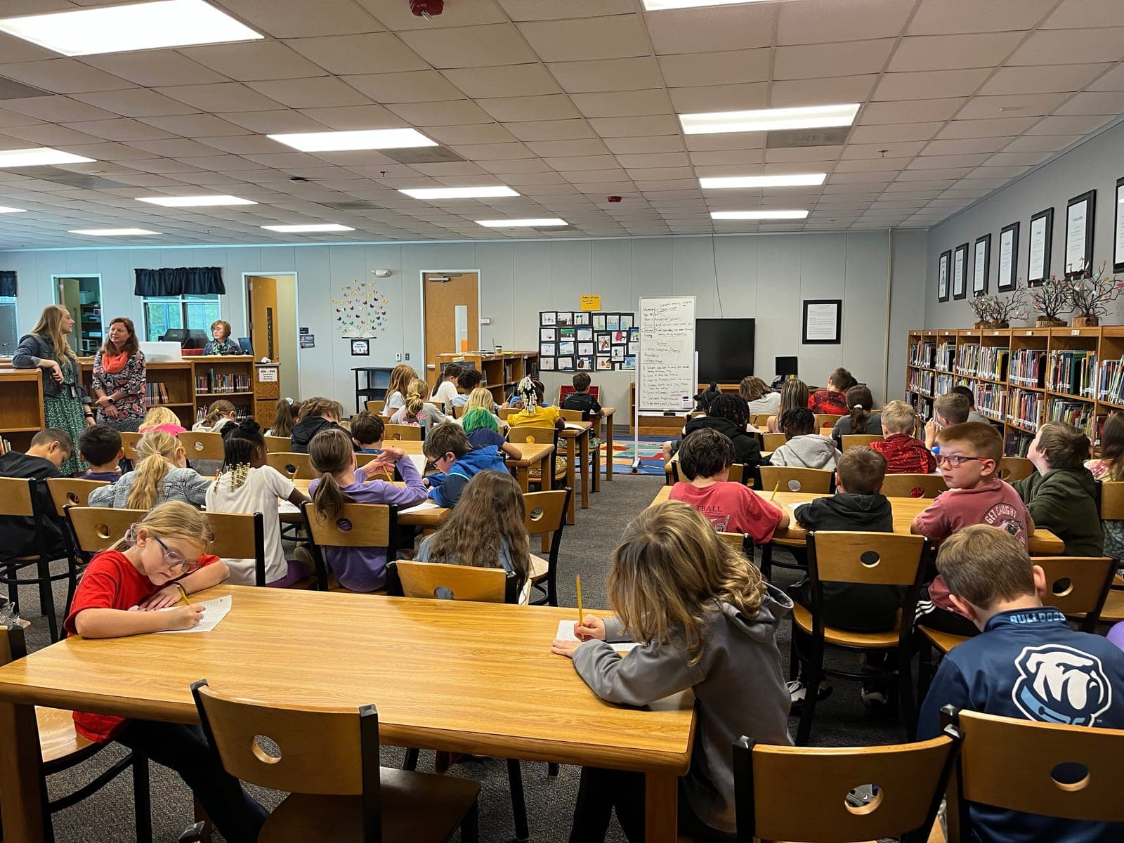Students writing at library tables during a visit with Liesl